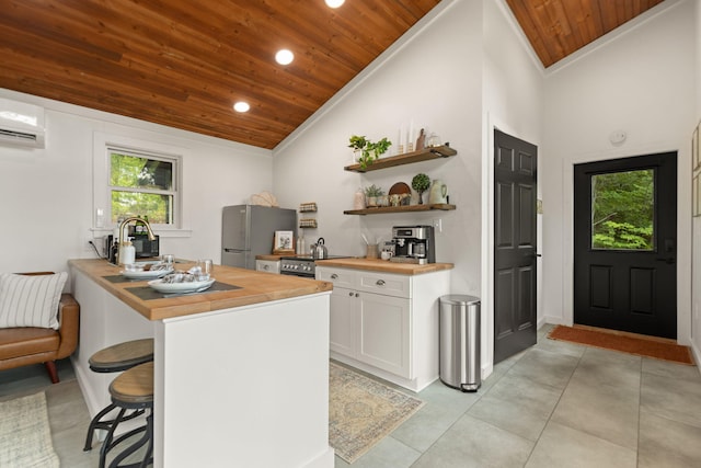 kitchen featuring butcher block countertops, stainless steel fridge, plenty of natural light, white cabinetry, and wooden ceiling