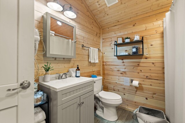 bathroom featuring toilet, vanity, wood walls, lofted ceiling, and visible vents