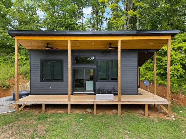 rear view of house featuring ceiling fan and a lawn