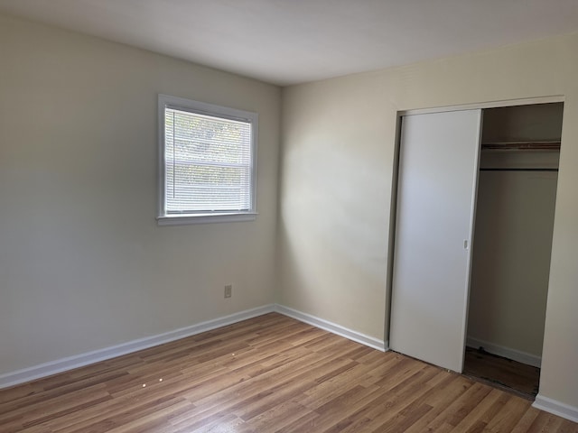 unfurnished bedroom featuring light wood-style floors, a closet, and baseboards