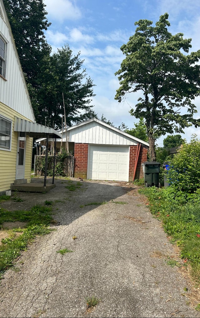 view of side of property featuring an outbuilding, driveway, a garage, brick siding, and board and batten siding