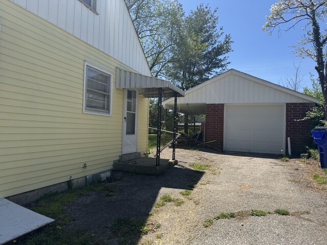 view of side of home featuring an outdoor structure, aphalt driveway, a detached garage, and board and batten siding