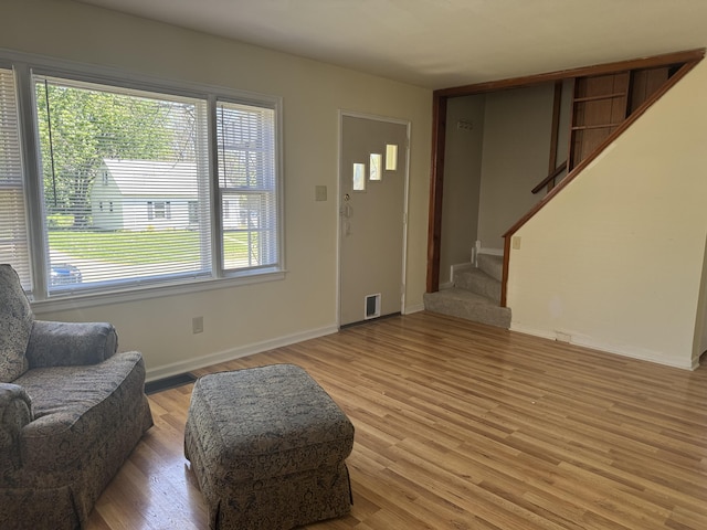 living room with stairway, baseboards, light wood-style floors, and visible vents