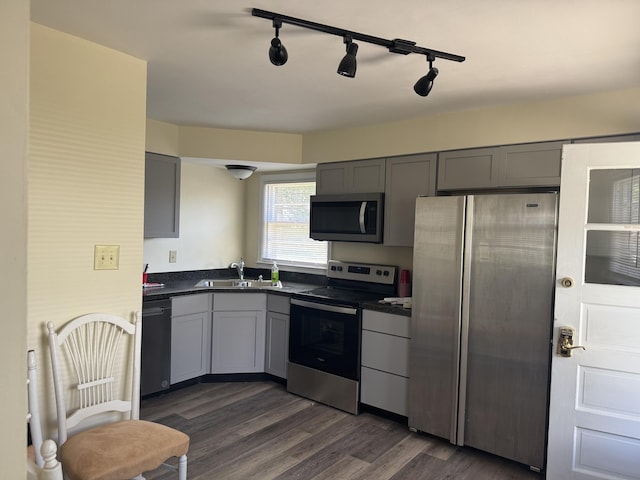 kitchen featuring gray cabinets, dark countertops, appliances with stainless steel finishes, and a sink
