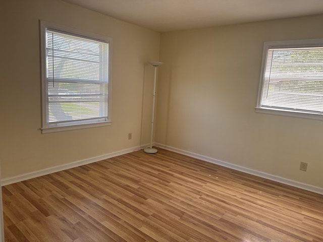 spare room featuring baseboards and light wood-style floors