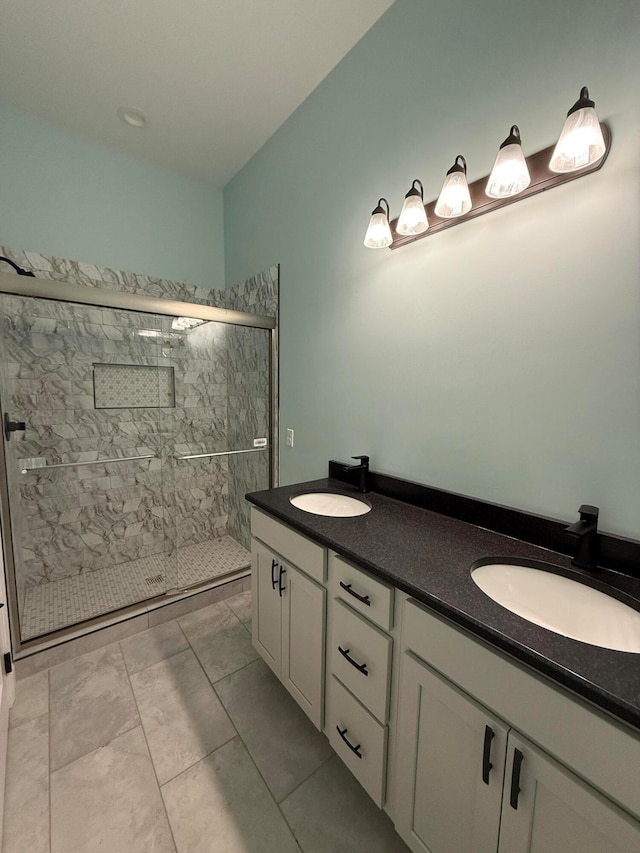 full bathroom with double vanity, a shower stall, and a sink