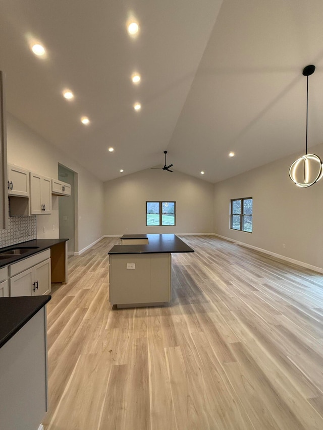 kitchen featuring dark countertops, plenty of natural light, a kitchen island, and light wood-style flooring