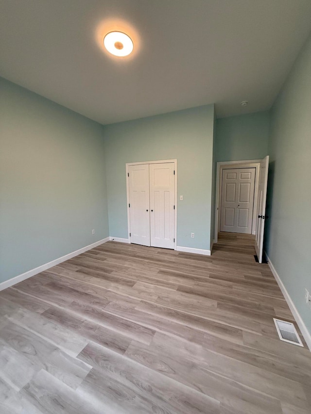 unfurnished bedroom with a closet, visible vents, light wood-style flooring, and baseboards