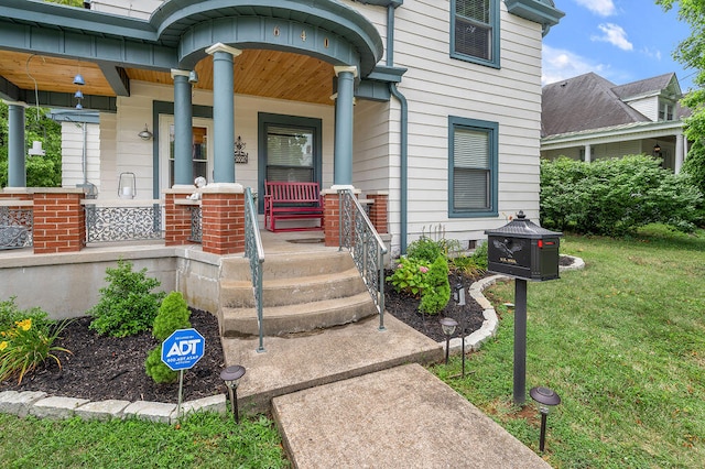 doorway to property featuring covered porch and a yard