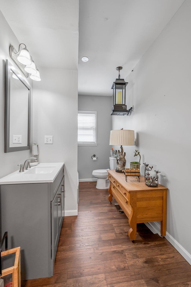 bathroom featuring vanity, wood finished floors, toilet, and baseboards