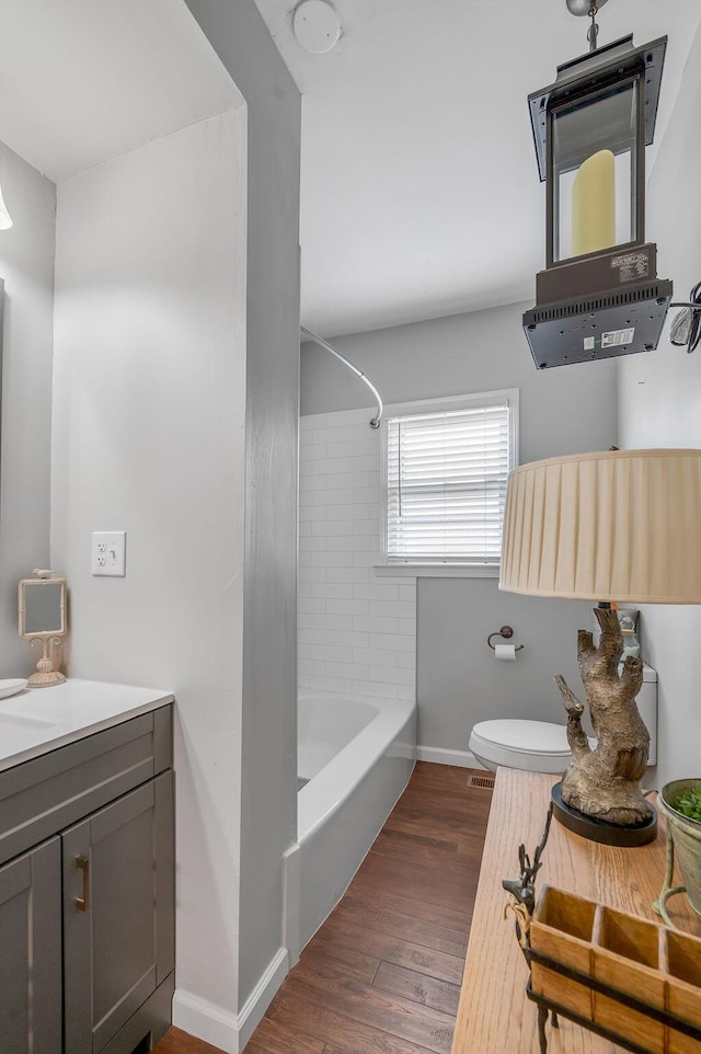 full bathroom with bathtub / shower combination, toilet, wood finished floors, vanity, and baseboards