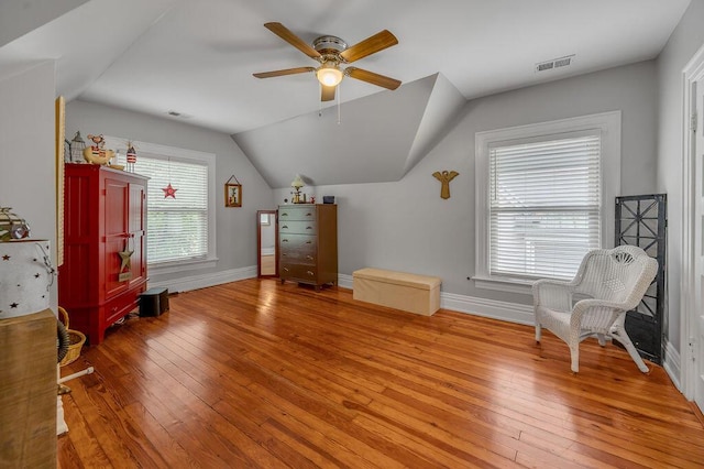 interior space featuring lofted ceiling, light wood finished floors, baseboards, and visible vents