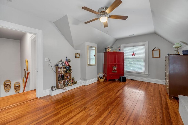 additional living space with lofted ceiling, visible vents, ceiling fan, wood finished floors, and baseboards