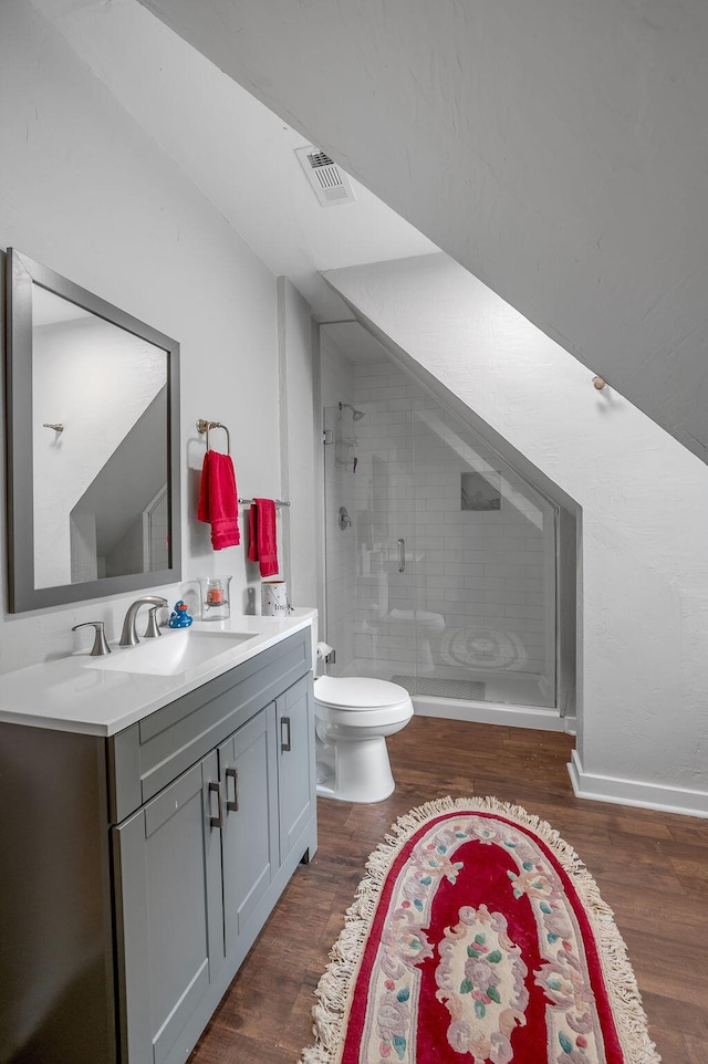 bathroom featuring visible vents, toilet, a stall shower, vanity, and wood finished floors