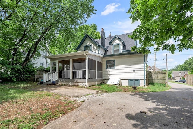 view of front of home featuring a sunroom, fence, and a chimney