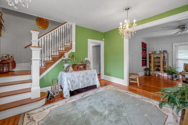 interior space with baseboards, wood finished floors, and ceiling fan with notable chandelier