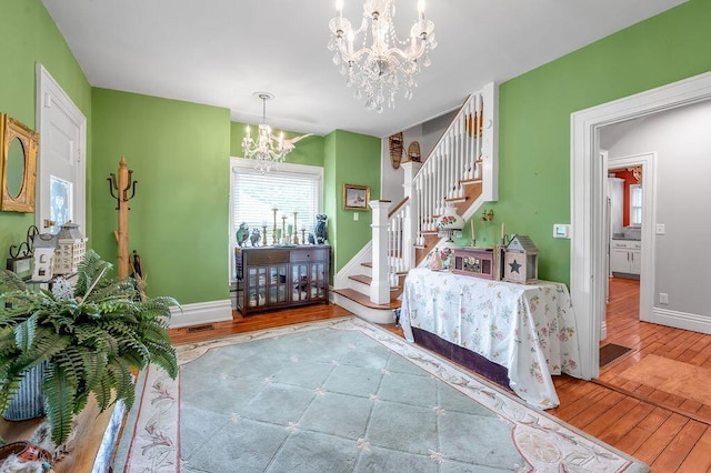 bedroom with a chandelier, visible vents, baseboards, and wood finished floors