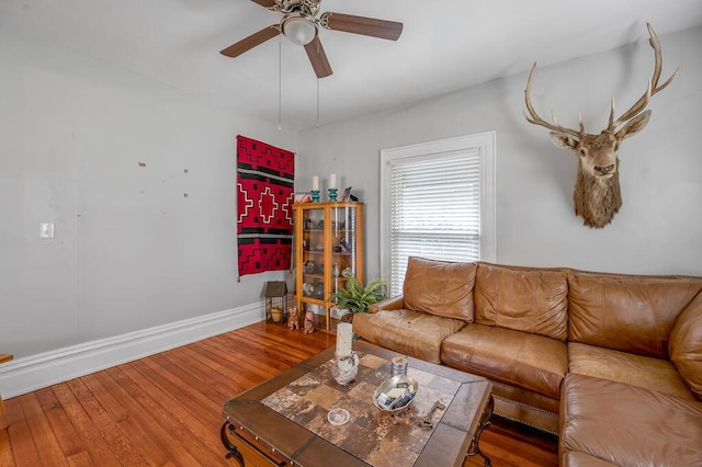 living room with ceiling fan, baseboards, and wood finished floors