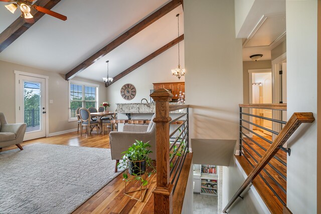 living room with high vaulted ceiling, ceiling fan with notable chandelier, light hardwood / wood-style floors, and beam ceiling