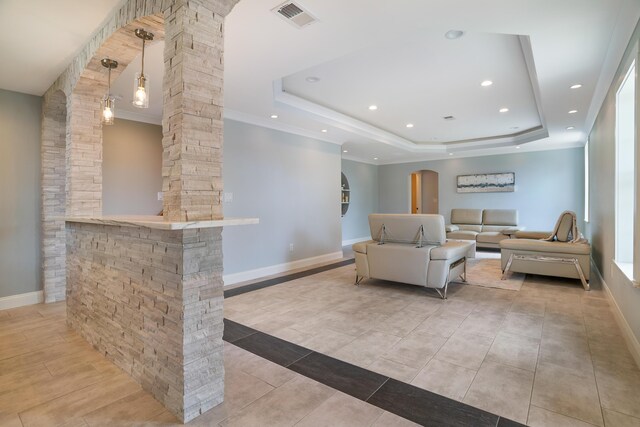 living room with decorative columns, a tray ceiling, and light tile patterned floors