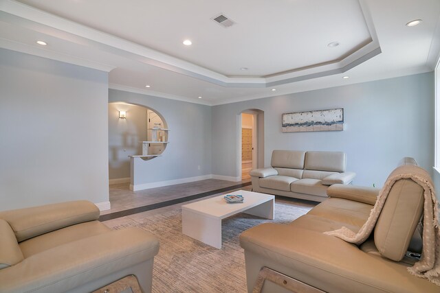 living room with a raised ceiling and ornamental molding