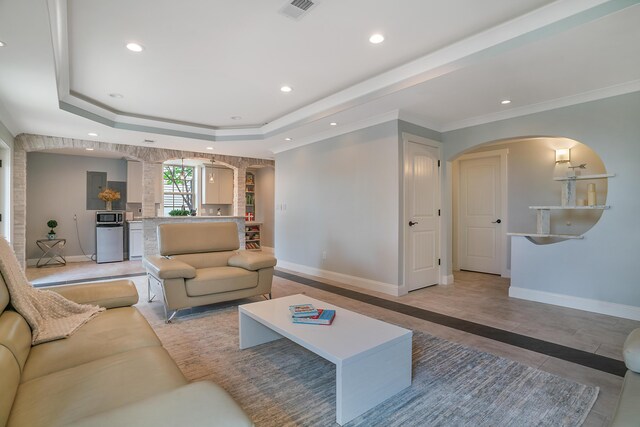 tiled living room with a raised ceiling and ornamental molding