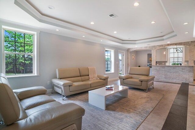 living room with plenty of natural light, tile patterned flooring, and a raised ceiling