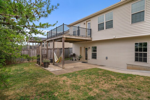 back of house featuring a deck, a lawn, and a patio area