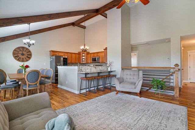 living room with ceiling fan with notable chandelier, light hardwood / wood-style flooring, and high vaulted ceiling