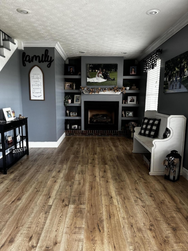 living room featuring hardwood / wood-style floors, crown molding, built in features, and a textured ceiling