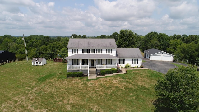 view of front of property featuring covered porch, a shed, a front lawn, and a garage