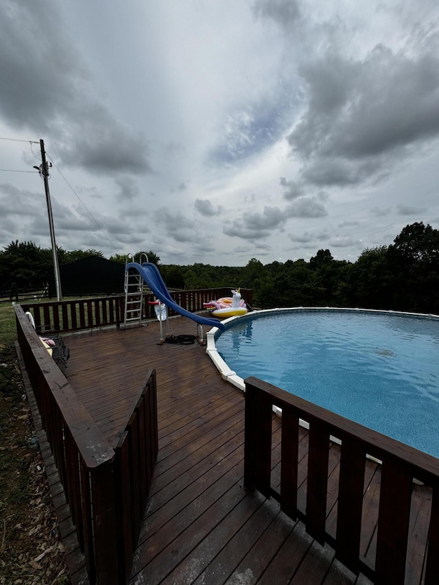 view of swimming pool featuring a water slide and a wooden deck