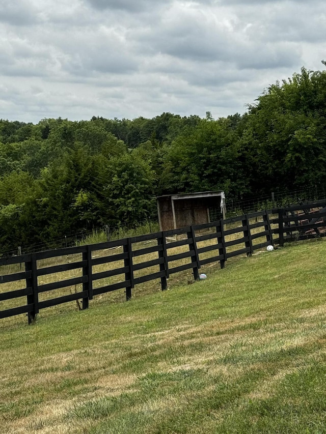 view of gate with a lawn and a rural view