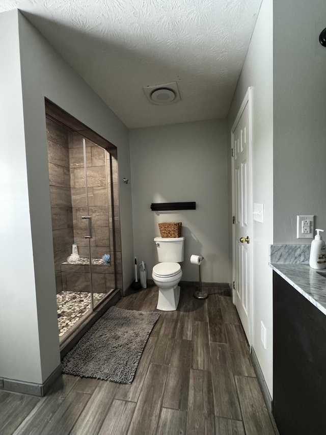 bathroom featuring an enclosed shower, a textured ceiling, and toilet