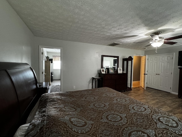 bedroom with ceiling fan, dark hardwood / wood-style floors, and a textured ceiling