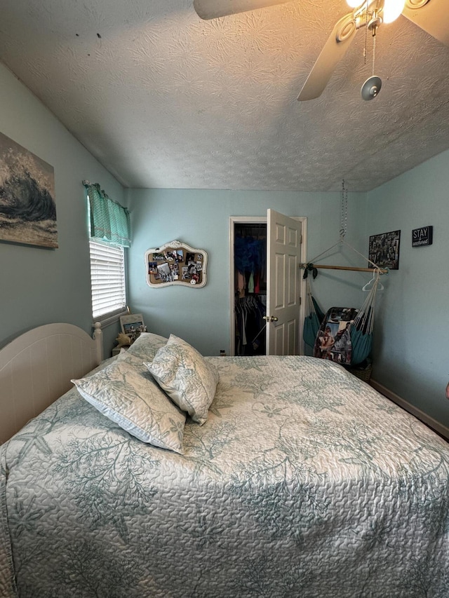 bedroom featuring ceiling fan, a walk in closet, a textured ceiling, and a closet