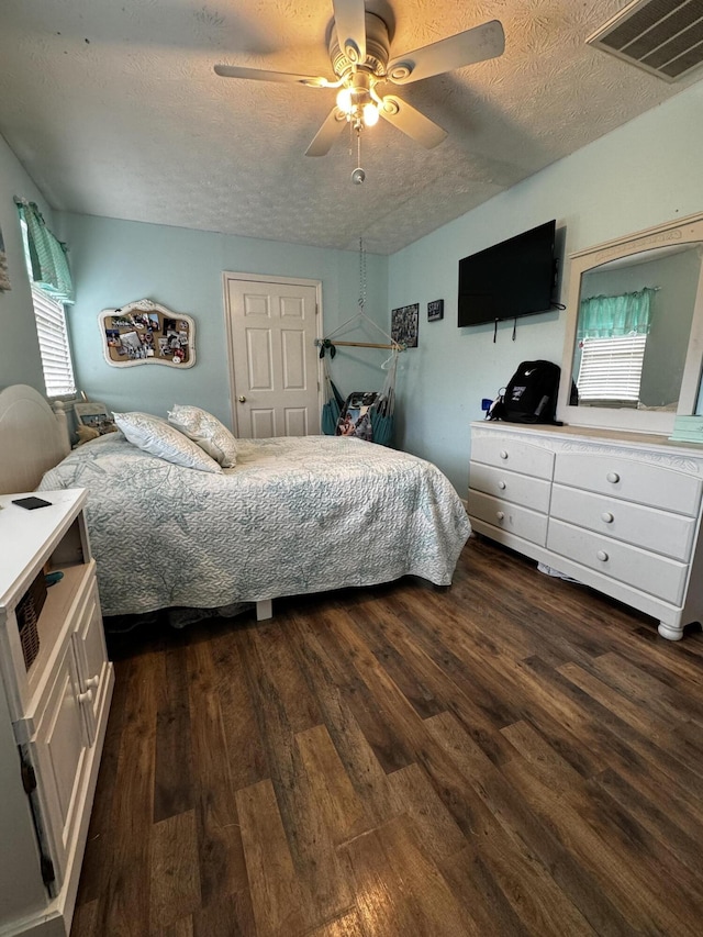 bedroom featuring a textured ceiling, ceiling fan, and dark wood-type flooring