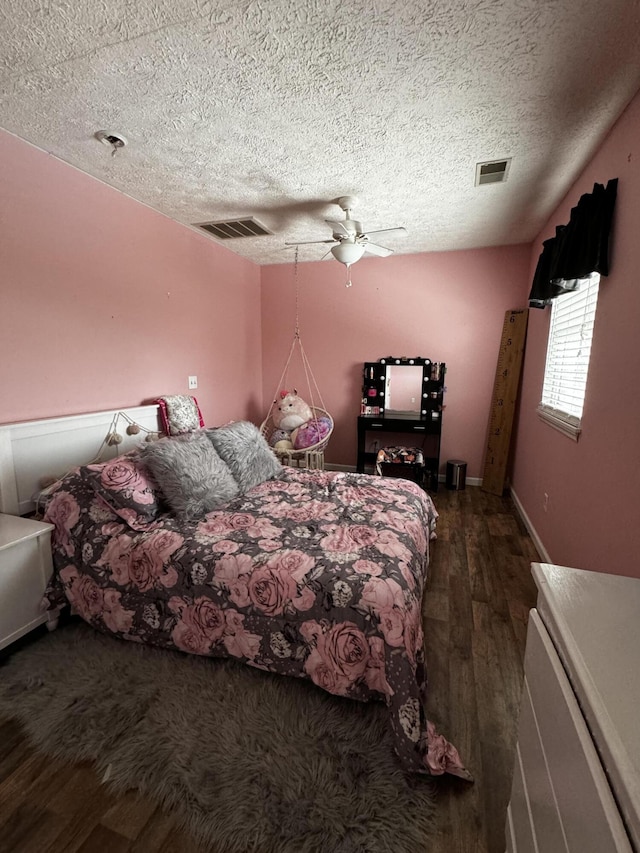 bedroom featuring ceiling fan, dark hardwood / wood-style flooring, and a textured ceiling