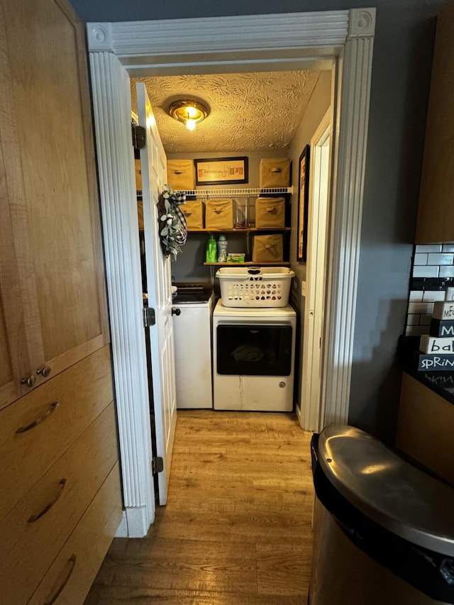 washroom featuring a textured ceiling, light wood-type flooring, and separate washer and dryer