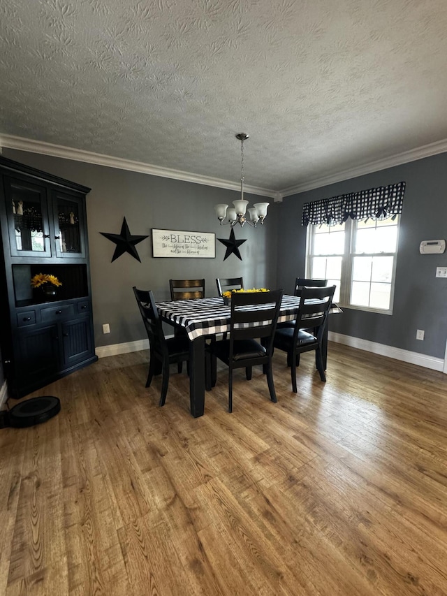 dining area featuring ornamental molding, a textured ceiling, hardwood / wood-style flooring, and a notable chandelier