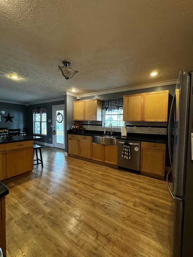 kitchen featuring sink, stainless steel appliances, crown molding, a textured ceiling, and hardwood / wood-style flooring