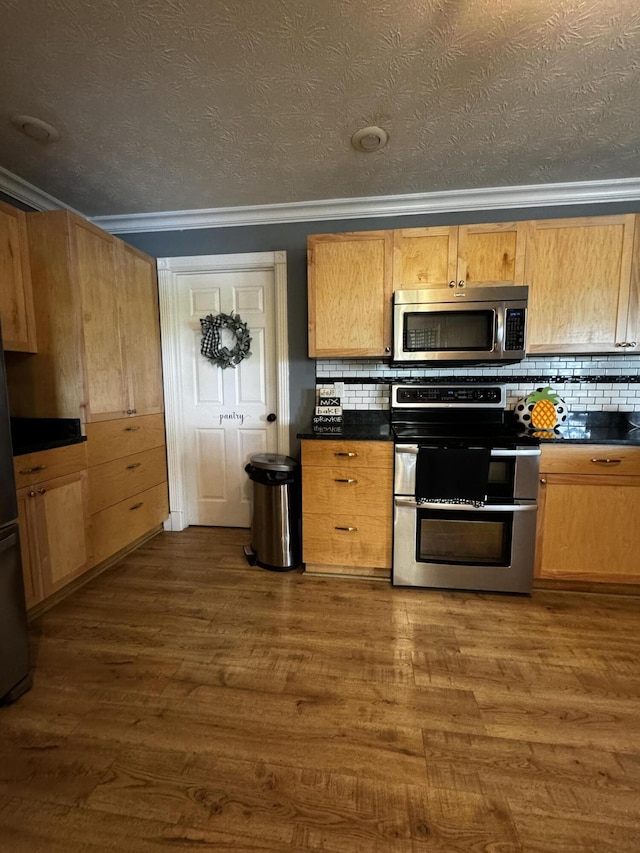 kitchen featuring backsplash, dark hardwood / wood-style flooring, crown molding, and appliances with stainless steel finishes