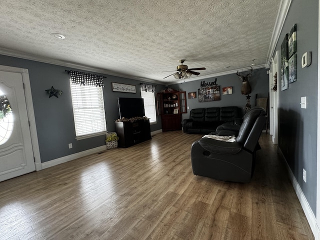 unfurnished living room featuring ceiling fan, hardwood / wood-style flooring, a textured ceiling, and ornamental molding