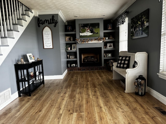 sitting room featuring hardwood / wood-style floors, a textured ceiling, built in features, and ornamental molding