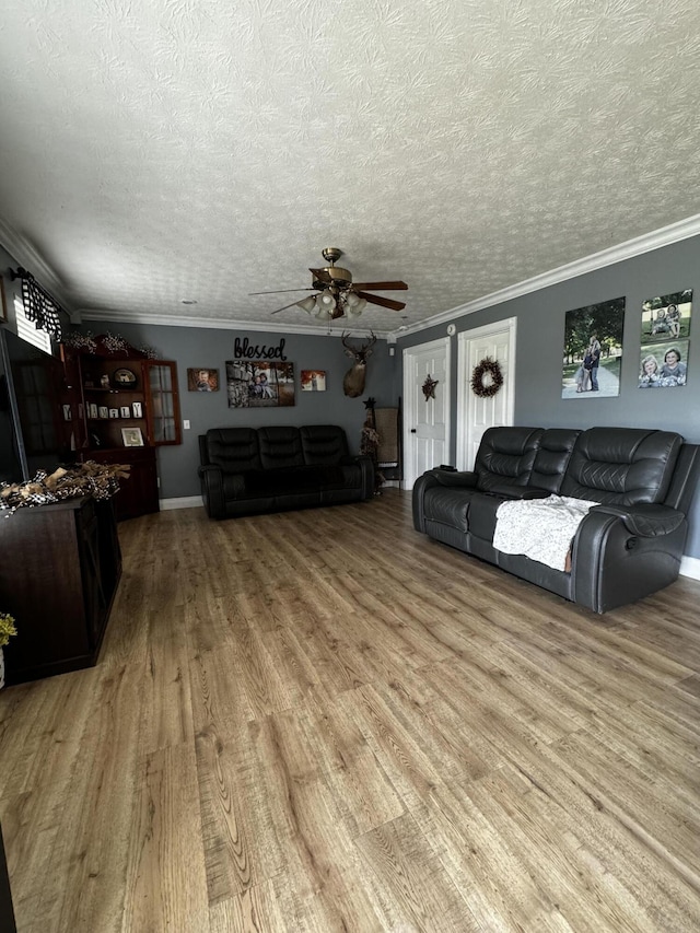 living room featuring a textured ceiling, ceiling fan, and crown molding