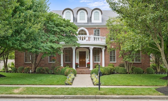 colonial inspired home with brick siding, a front lawn, a porch, and a balcony