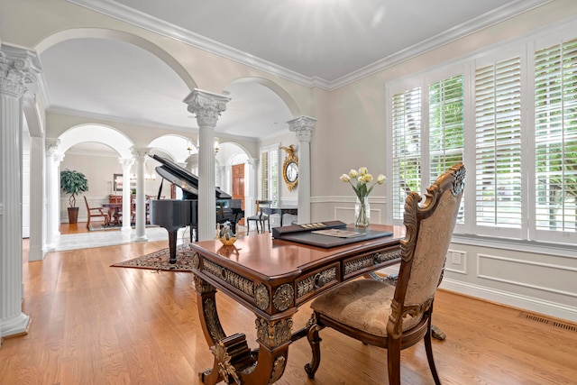 dining area featuring light hardwood / wood-style flooring, crown molding, and decorative columns