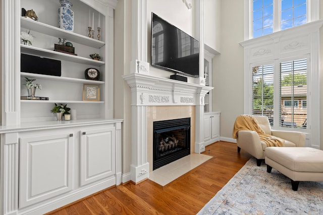 living room featuring hardwood / wood-style flooring, built in features, and a fireplace