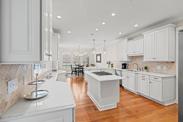 kitchen with light hardwood / wood-style flooring, crown molding, decorative light fixtures, and kitchen peninsula