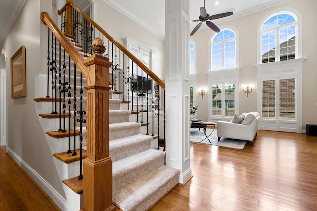 staircase with crown molding, hardwood / wood-style flooring, and a towering ceiling